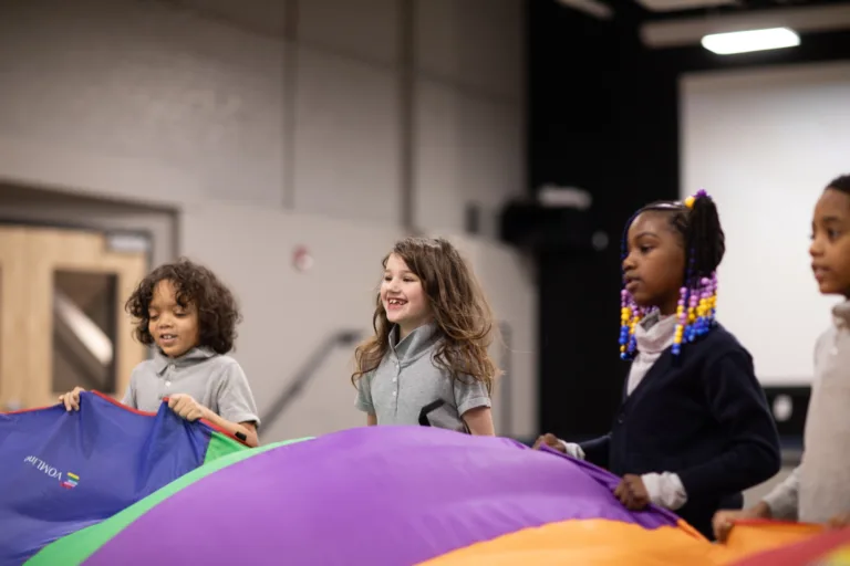 A group of students playing with a giant parachute in a gym class