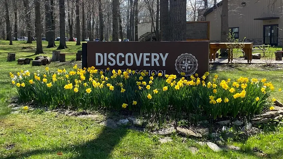 Discovery-Charter-School-Sign Discovery Charter School sign surrounded by blooming daffodils on the wooded campus.