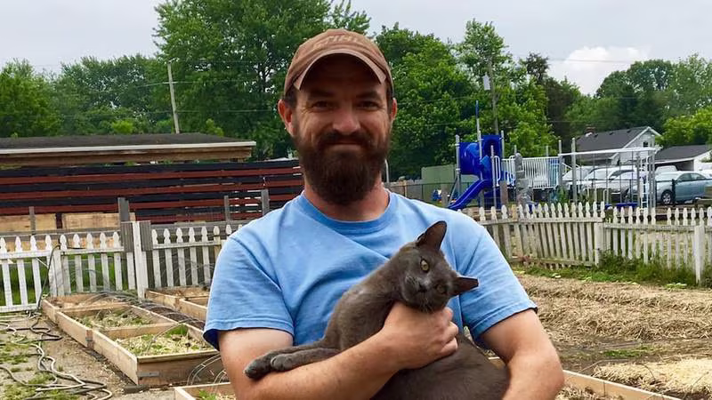 Man holding a gray cat in the garden at Paramount Brookside.