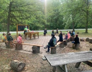 Students participate in an outdoor learning activity in a wooded classroom setting.