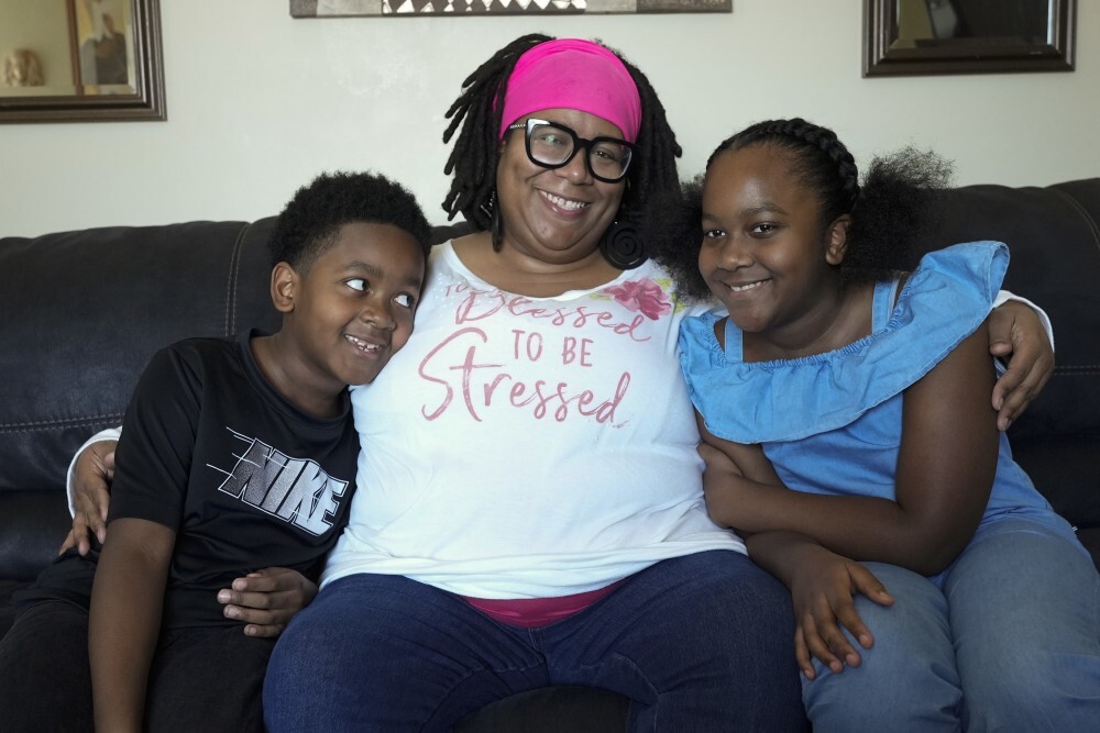 Parent sitting on a couch with two smiling children.