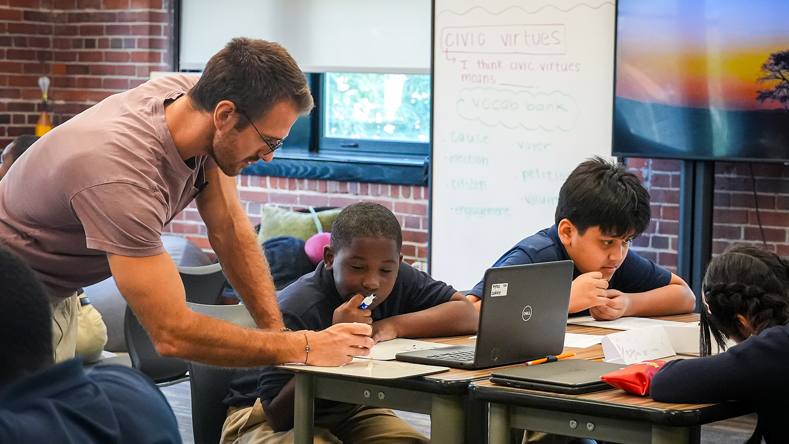 Englewood-apply-hero Paramount Englewood teacher helping students with a classroom assignment while working at their desks