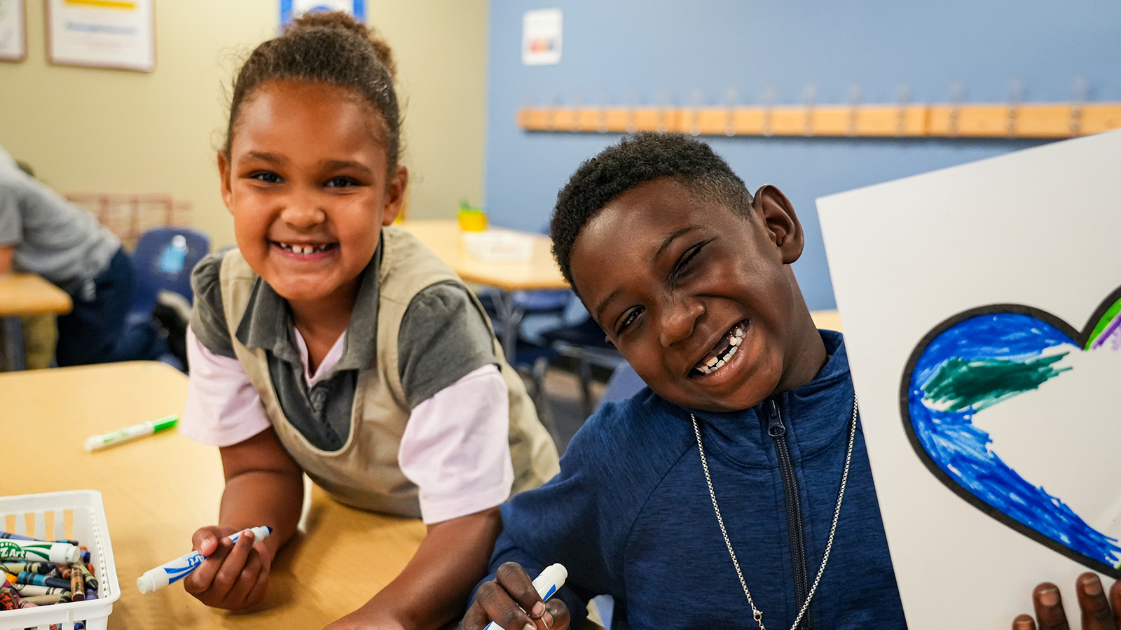 brookside-parent-center-hero Two smiling Paramount Brookside students displaying colorful artwork during a classroom activity