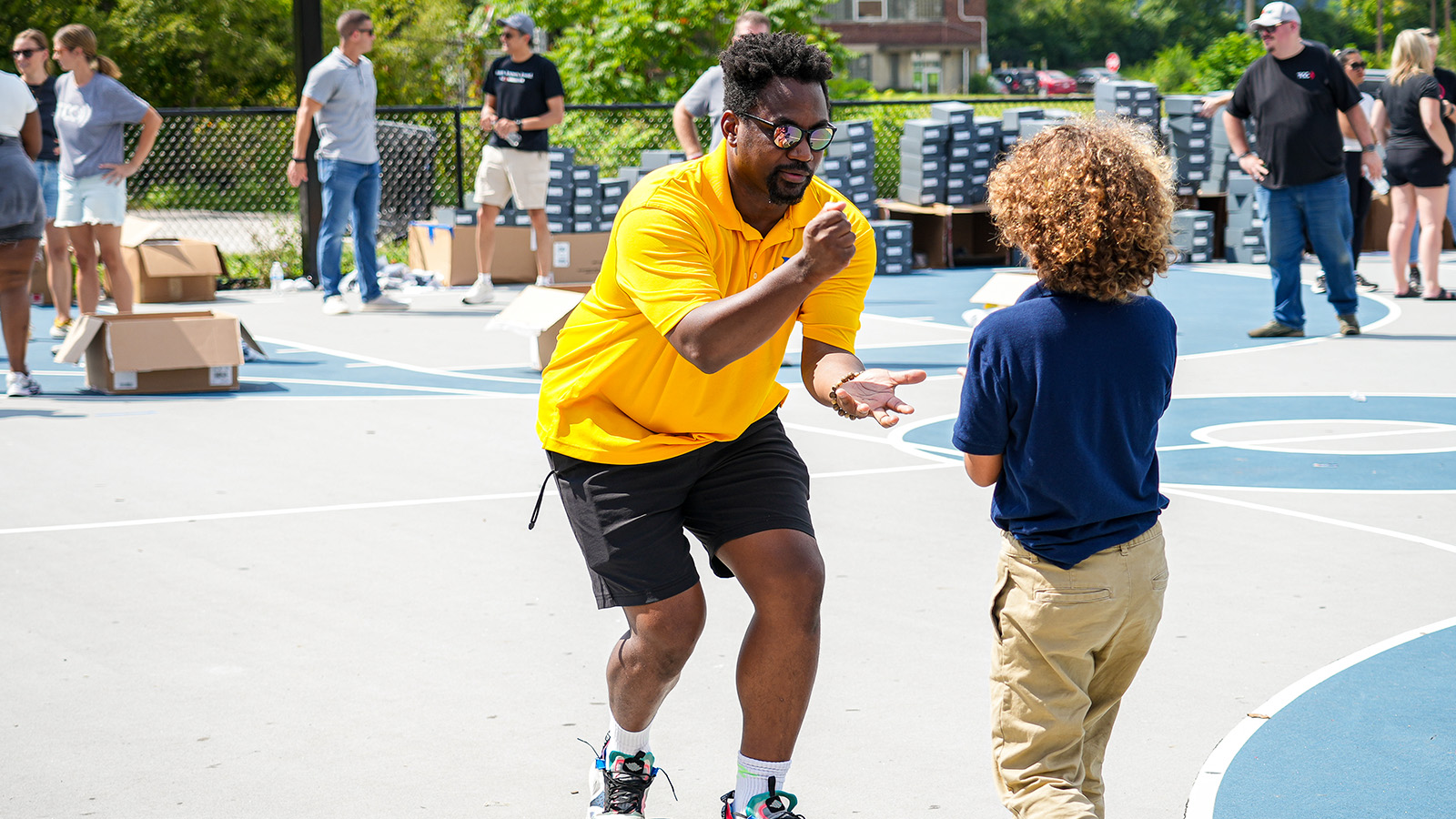 englewood-calendar-hero Paramount Englewood staff member interacting with a student on the outdoor basketball court during a school community event