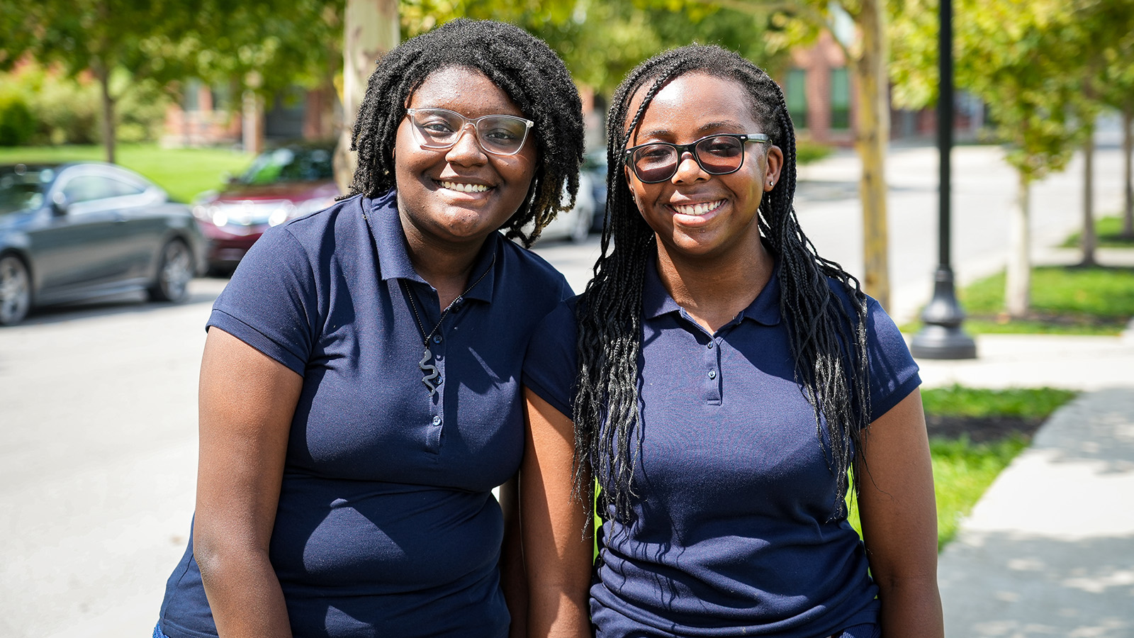 Two smiling Paramount Englewood staff members posing together outside the school