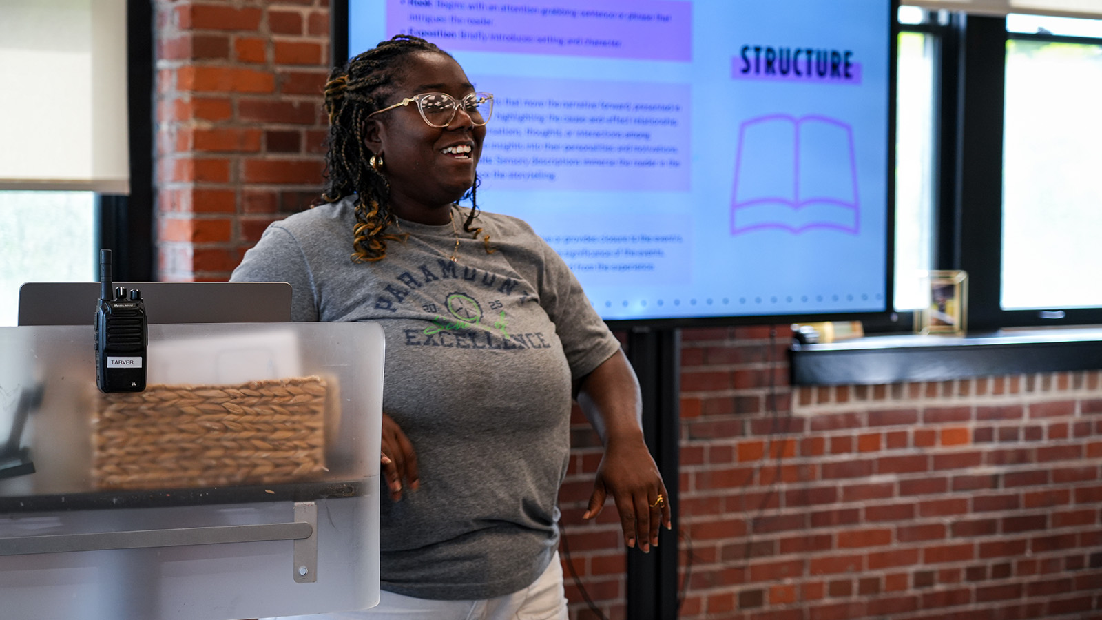 englewood-staff-hero Smiling Paramount Englewood teacher standing in front of a classroom presentation on writing structure