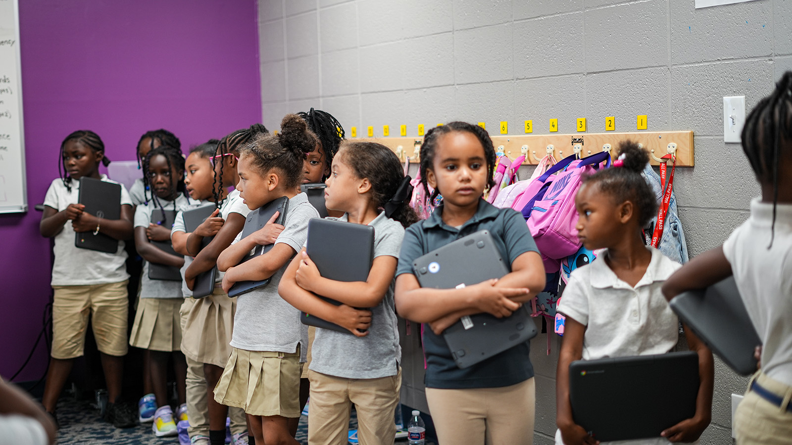 Girls IN STEM Academy students holding laptops while preparing for a classroom learning activity