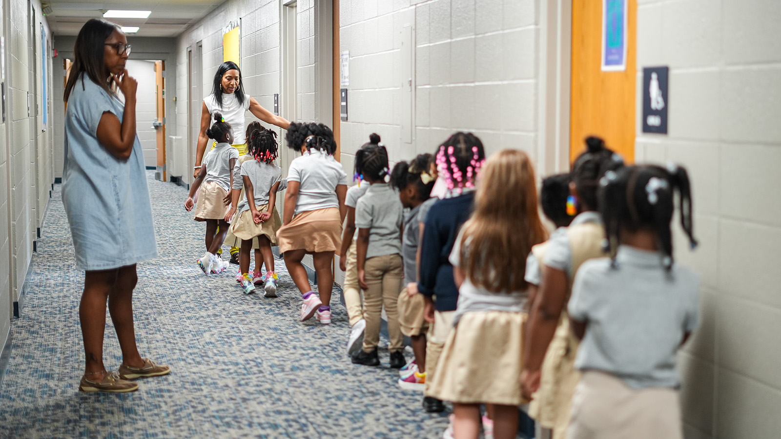 Girls IN STEM Academy students walking through the school hallway with staff members supervising