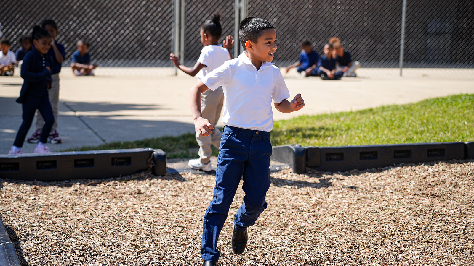 Andrew J. Brown Academy student smiling and running across the school playground during outdoor recess