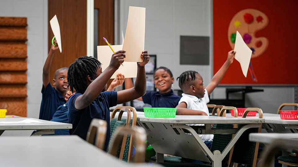 ajb-features-2 Andrew J. Brown Academy students enthusiastically raising their worksheets during an interactive classroom activity