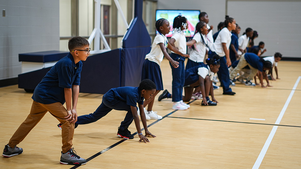 Andrew J. Brown Academy students preparing for a running activity during physical education class in the school gymnasium