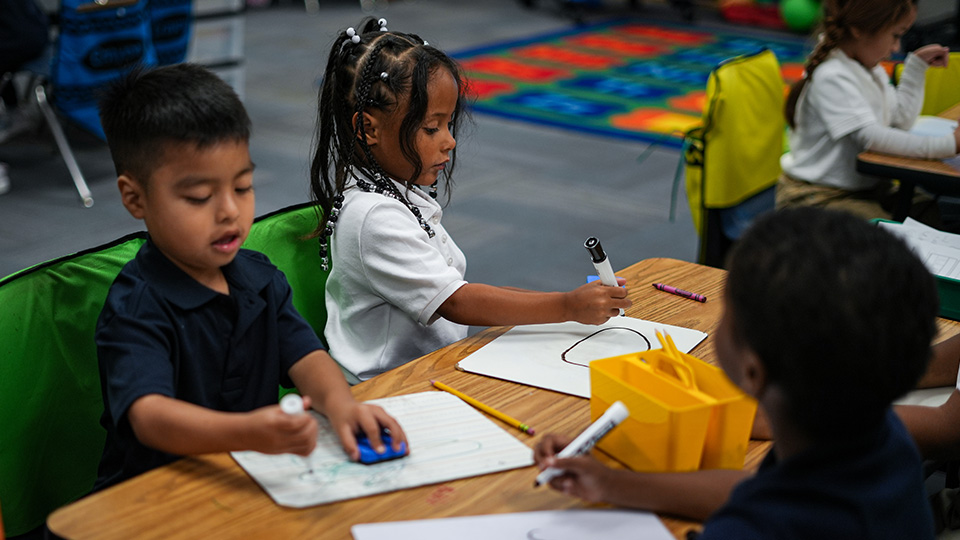 Andrew J. Brown Academy students practicing writing and drawing on individual whiteboards during a classroom activity