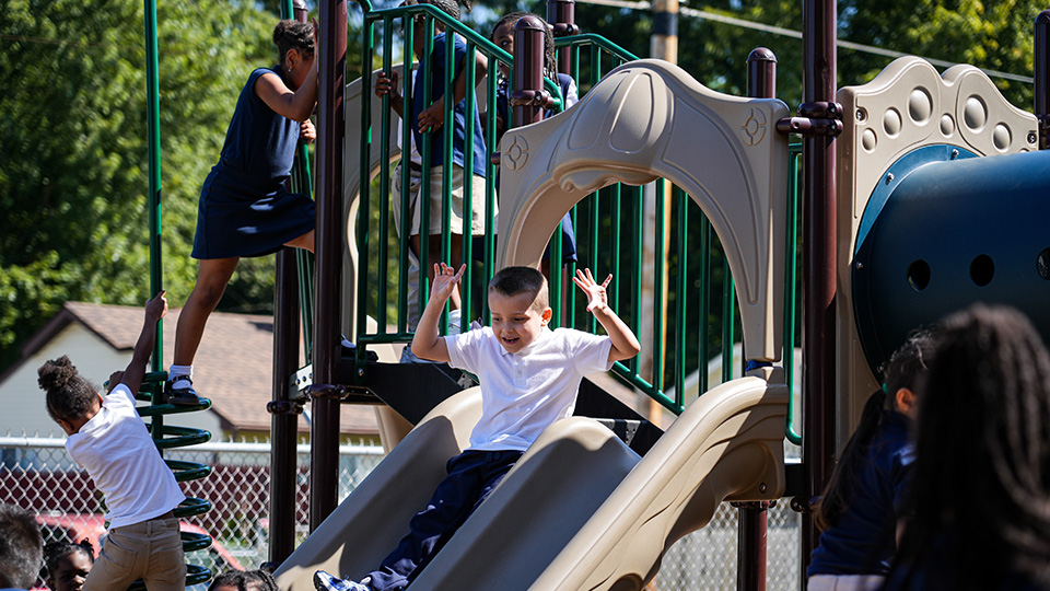 Andrew J. Brown Academy students climbing and sliding on playground equipment during outdoor recess