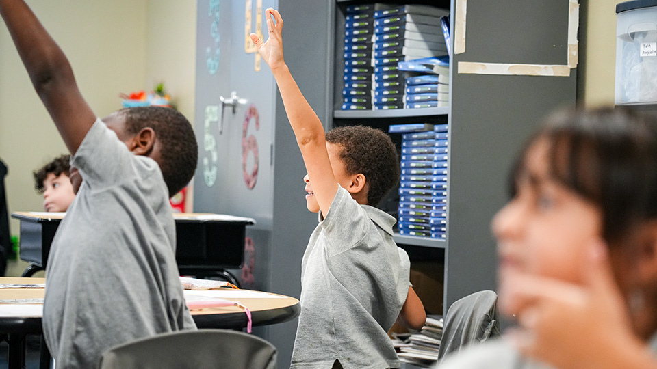 Paramount Brookside students raising their hands to participate in a classroom lesson