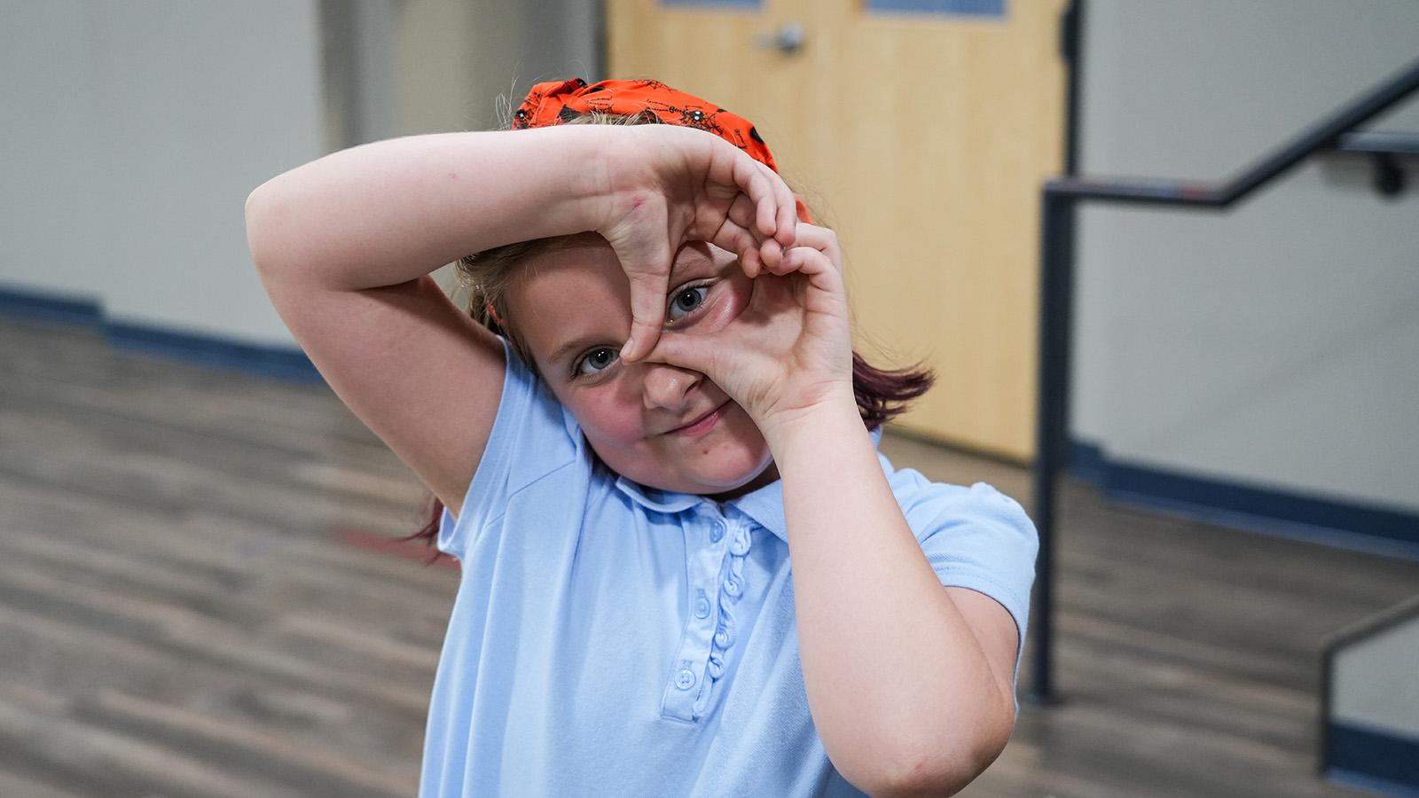 contact-hero Paramount student smiling and making a playful frame around her eyes with her hands