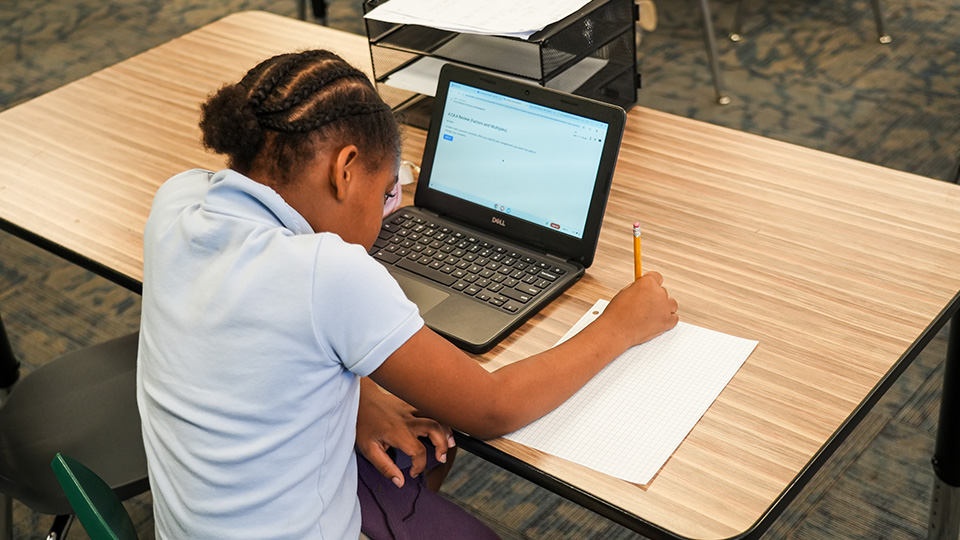 cottage-home-features-1 Paramount Cottage Home student completing a written assignment at a classroom desk with a laptop