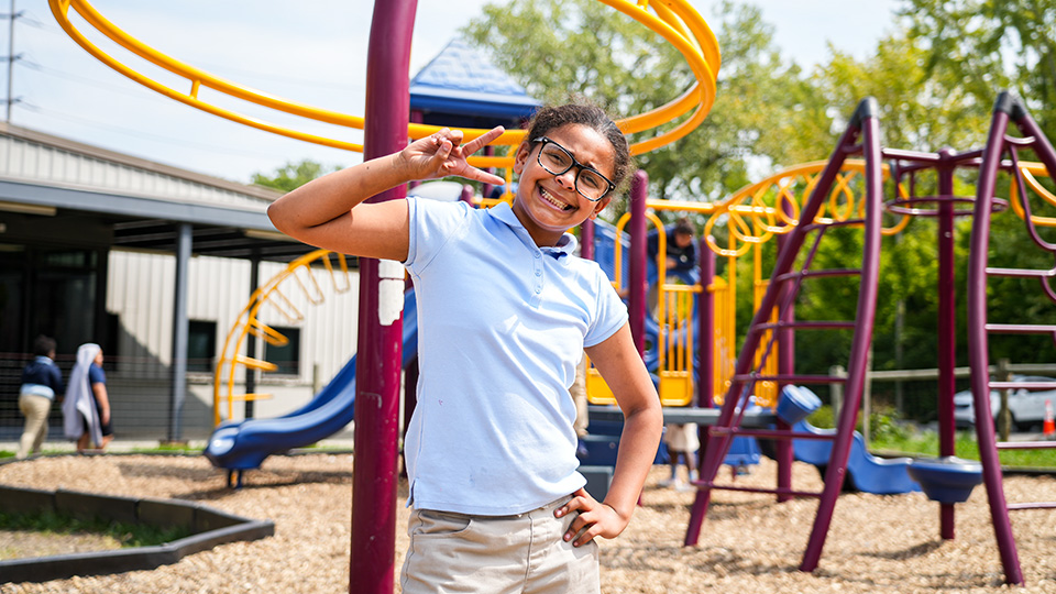 Smiling Paramount Cottage Home student posing on the school playground with colorful climbing equipment in the background