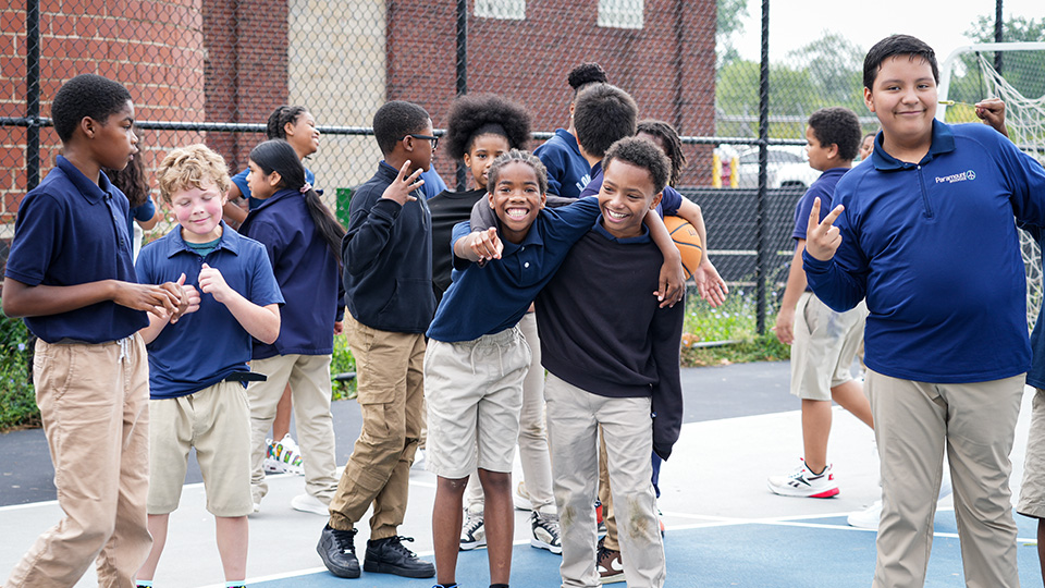 Paramount Englewood students smiling and posing together on the outdoor basketball court