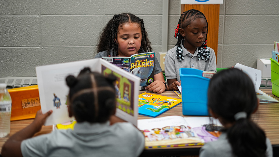 Girls IN STEM Academy students reading books together during a small-group classroom activity