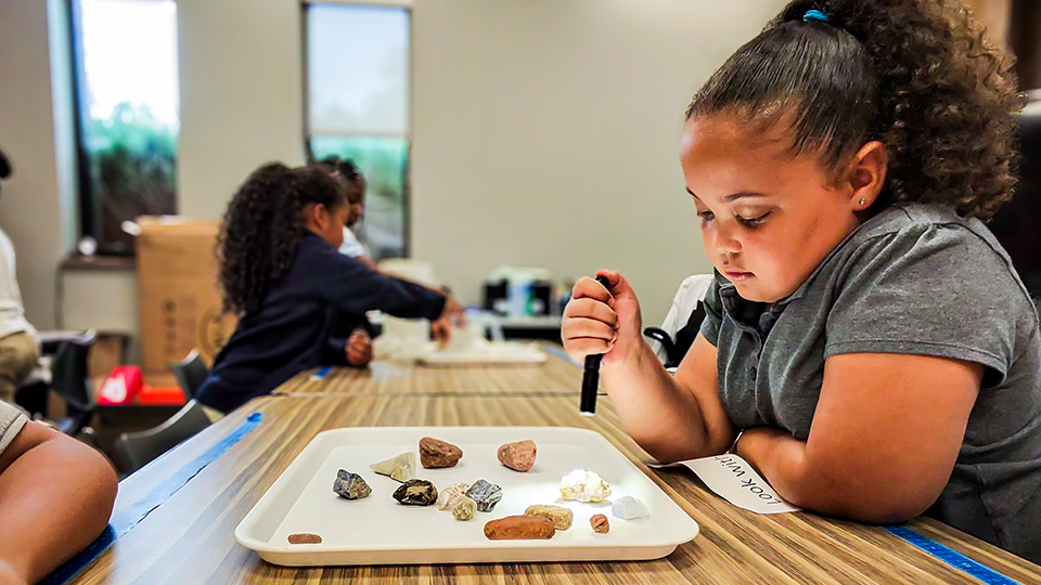 gisa-features-2 Girls IN STEM Academy student examining a collection of rocks and minerals during a hands-on science activity