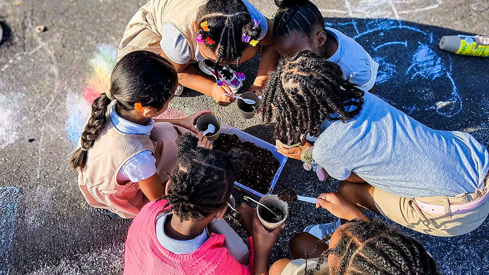 gisa-features-4 Girls IN STEM Academy students working together on a hands-on planting activity with soil and cups outdoors