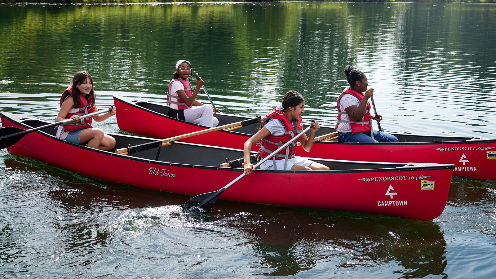 gisa-features-hero-updated Girls IN STEM Academy students wearing life jackets and paddling red canoes together on a lake during an outdoor learning adventure