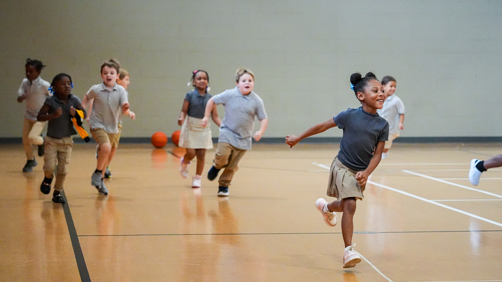 Paramount Lafayette students running and playing together during a physical education activity in the school gymnasium