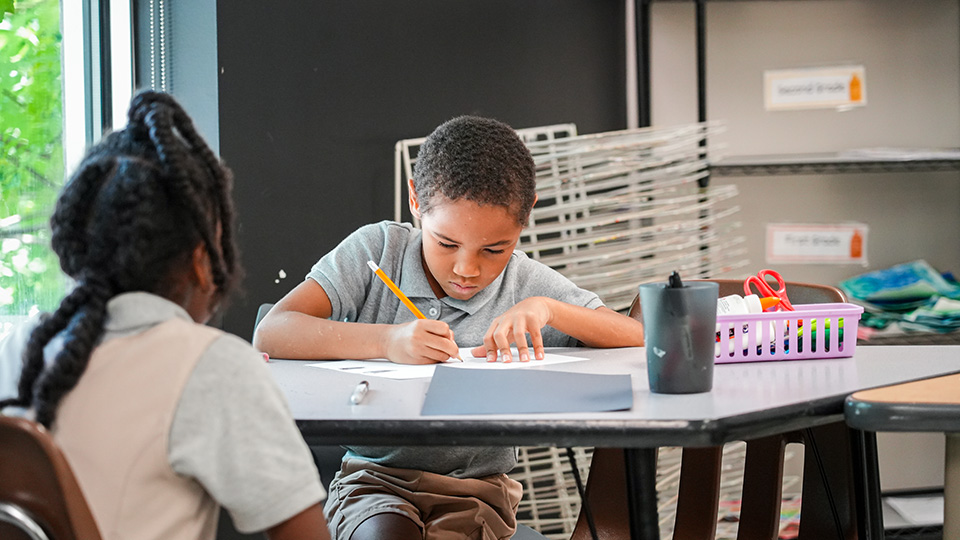 Paramount Lafayette student concentrating on a writing assignment at a classroom table
