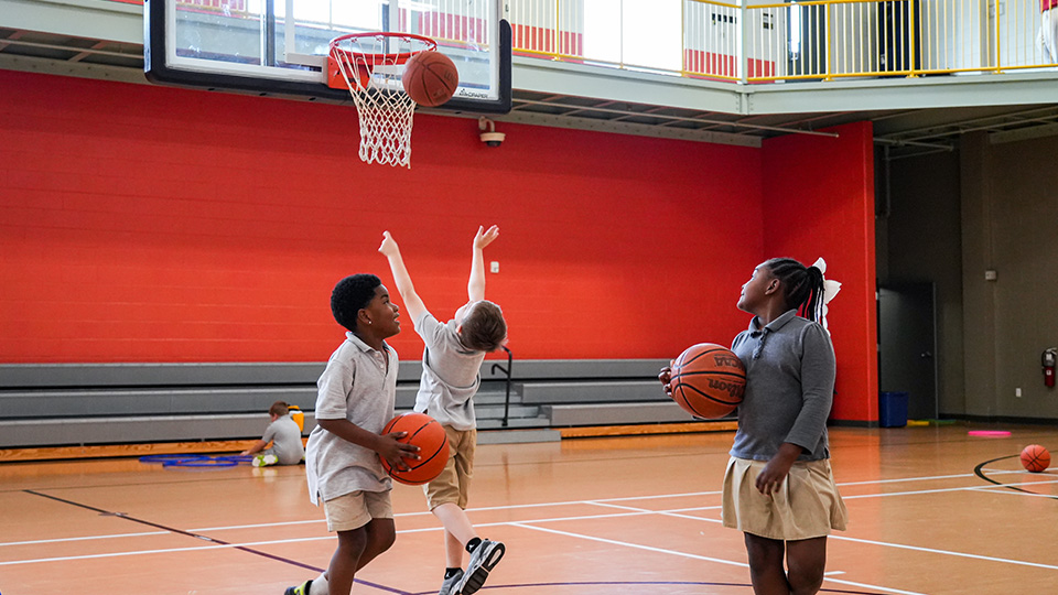 Paramount Lafayette students practicing basketball and shooting hoops during physical education class in the school gymnasium