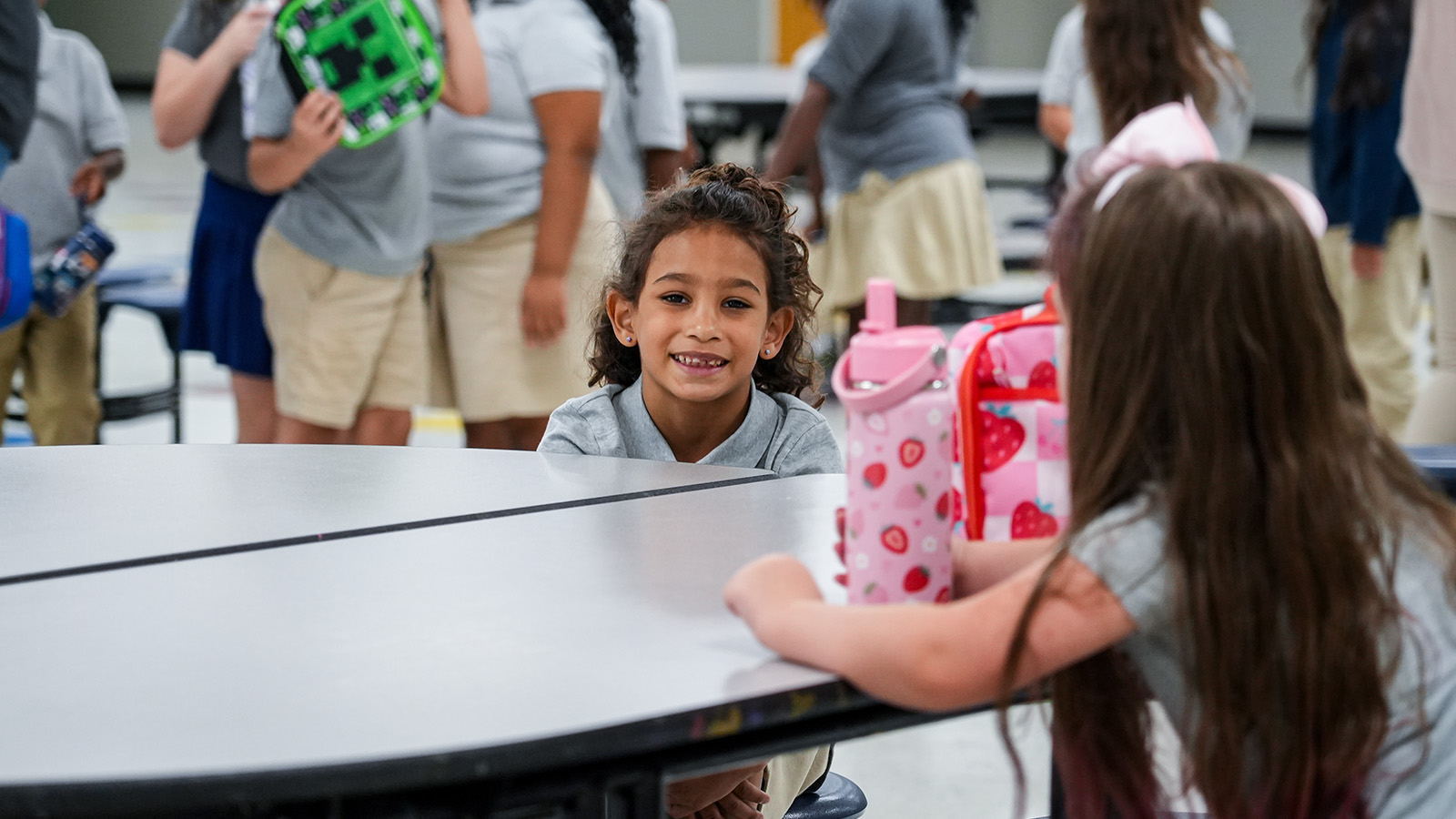 Smiling Paramount Lafayette student sitting across from a classmate at a table during a school activity