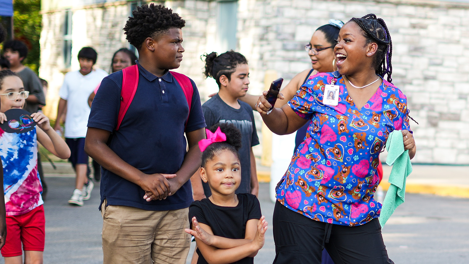 Paramount staff member smiling and interacting with students during an outdoor school event