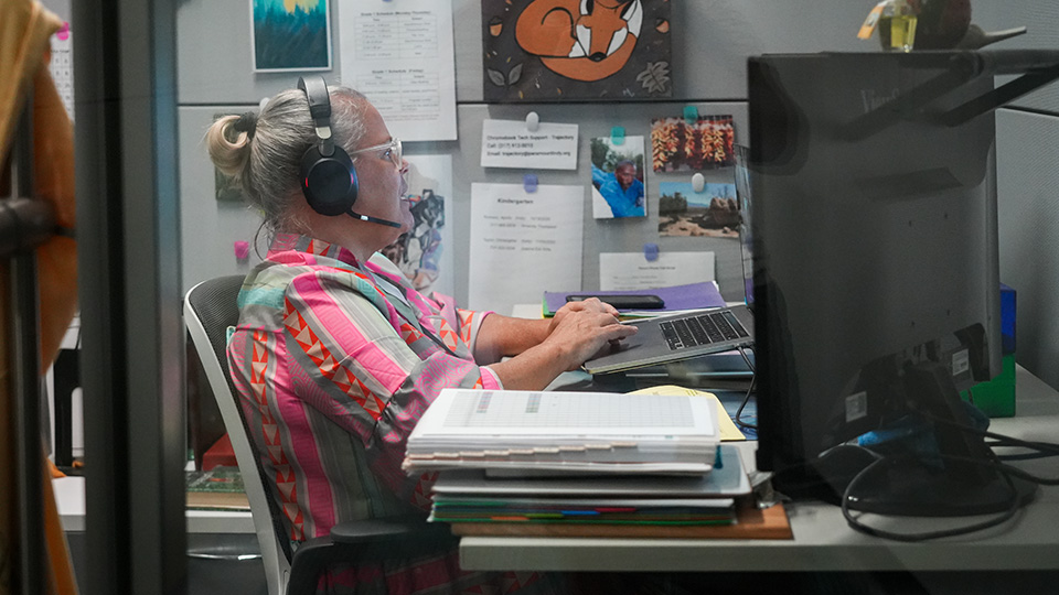 Paramount Online Academy teacher wearing a headset while working on a laptop at her desk to support virtual learning