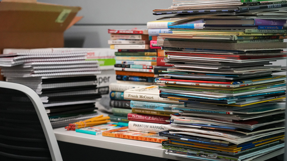 Stacks of books, notebooks, and educational materials organized for Paramount Online Academy students and teachers