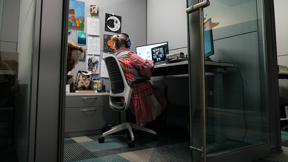 Paramount Online Academy teacher wearing a headset while leading a virtual classroom lesson with students from her workspace.