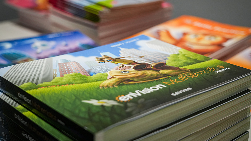 Stacks of enVision Mathematics textbooks and educational materials prepared for Paramount Online Academy students