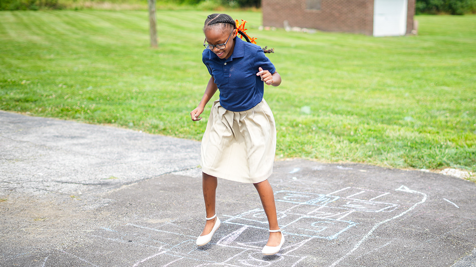 policies-and-handbooks-hero Paramount student playing hopscotch on a sidewalk chalk course outside the school