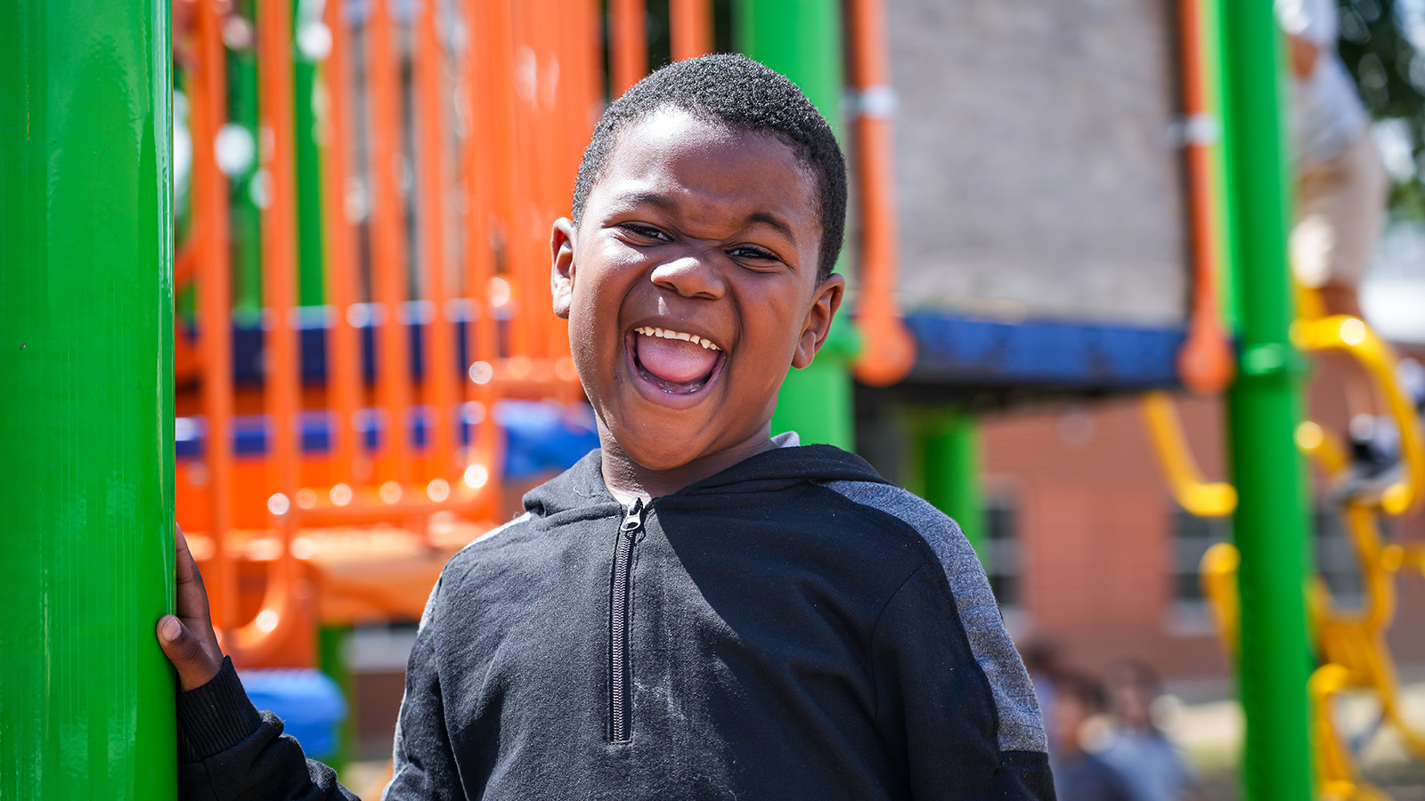Paramount South Bend student laughing and smiling on the school playground in front of colorful play equipment