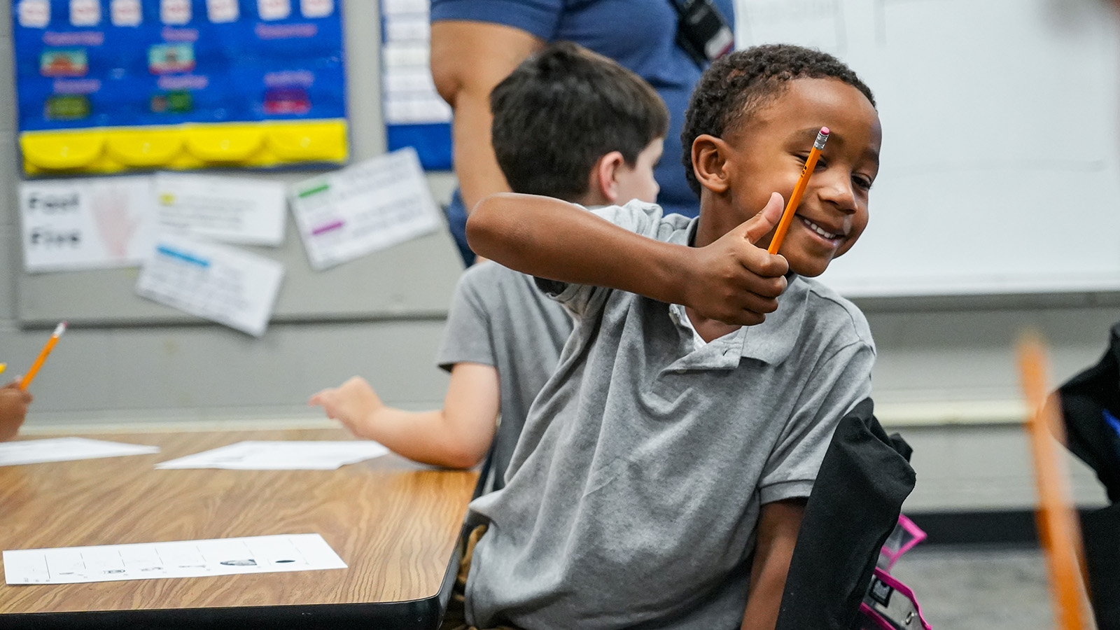 Smiling Paramount South Bend student giving a thumbs-up while holding a pencil during a classroom learning activity