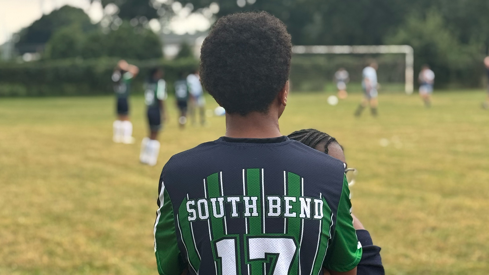 Paramount South Bend soccer player wearing a team jersey while watching classmates play on the field